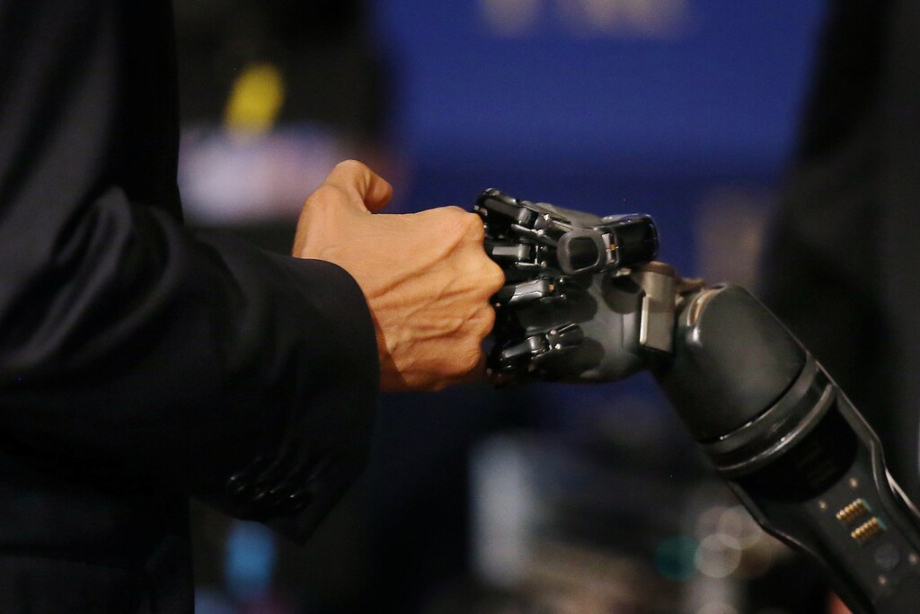 U.S. President Barack Obama gives a fist-bump to a robotic arm operated by Nathan Copeland, a quadriplegic brain implant patient who can experience the sensation of touch and control a remote robotic arm with his brain during a tour of the innovation projects at the White House Frontiers conference in Pittsburgh, U.S. October 13, 2016. REUTERS/Carlos Barria - RTSS5SG
