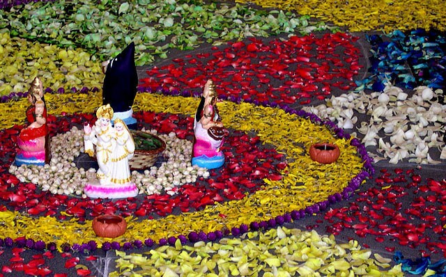 Radha Krishna Hindu deities at festival with traditional kolam floor art design