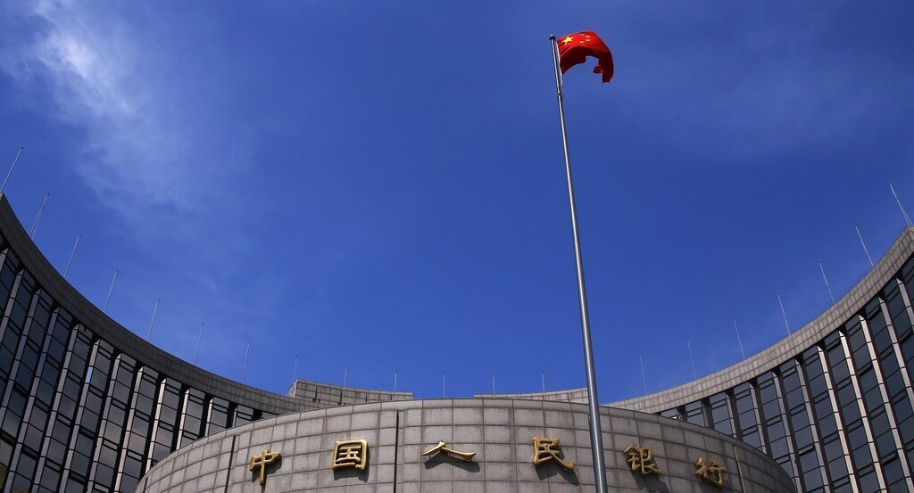 A Chinese national flag flutters in front of the headquarters of the People's Bank of China, China's central bank, in central Beijing, May 16, 2014. The bank is injecting a combined 500 billion yuan ($81.35 billion) of liquidity into the country's top banks, according to media reports, a sign that authorities are stepping up efforts to shore up a faltering economy. Picture taken May 16, 2014. REUTERS/Petar Kujundzic.