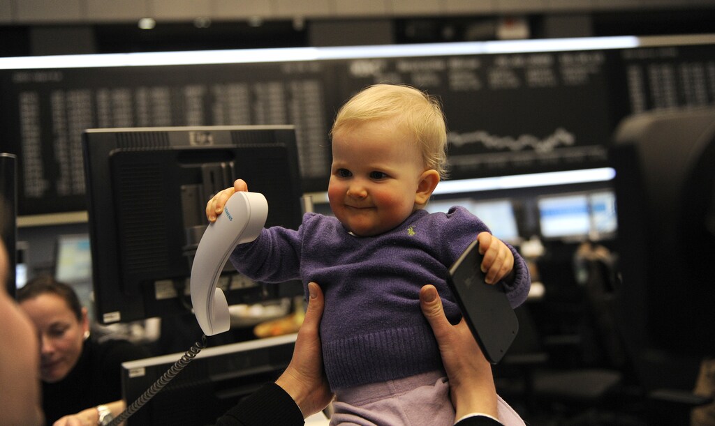 Eleven-month old toddler Vianne plays with a phone and a calculator as she sits on a traders desk in front of the German share price index DAX board at the German stock exchange in Frankfurt, February 20, 2009. Vianne and her mother visited a friend working as share trader at Frankfurt's stock exchange. REUTERS/Kai Pfaffenbach (GERMANY) - BM2E52K1AUZ01