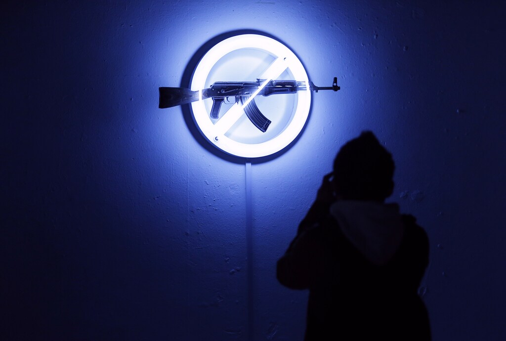 A visitor looks at Langlands & Bell's "Sign of the Times", at the AKA Peace exhibition at the Institute for Contemporary Art (ICA) in central London September 26, 2012. Bran Symondson, a former soldier, conceived the AKA Peace project, in which artists turn decommissioned AK47 assault rifles into works of art. REUTERS/Andrew Winning (BRITAIN - Tags: SOCIETY MILITARY TPX IMAGES OF THE DAY) - GM1E89R04UV01
