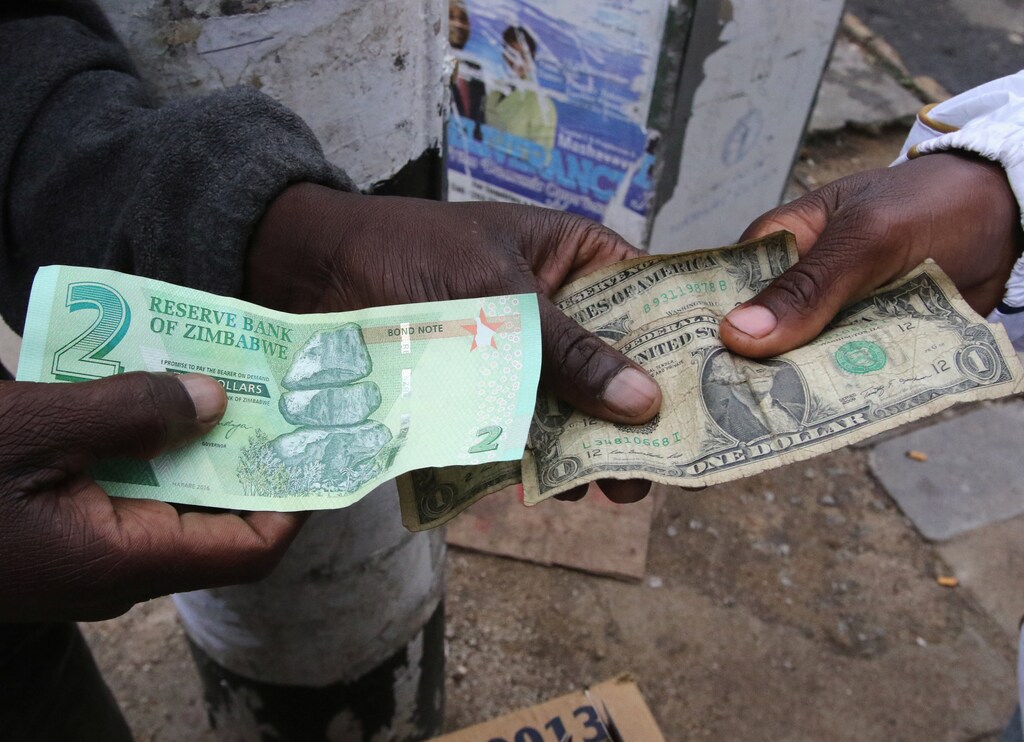 Illegal money changers pose while exchanging a new Zimbabwe bond note (L) and U.S. dollar notes in the capital Harare, Zimbabwe, November 28, 2016. REUTERS/Philimon Bulawayo - RC130F5B2970
