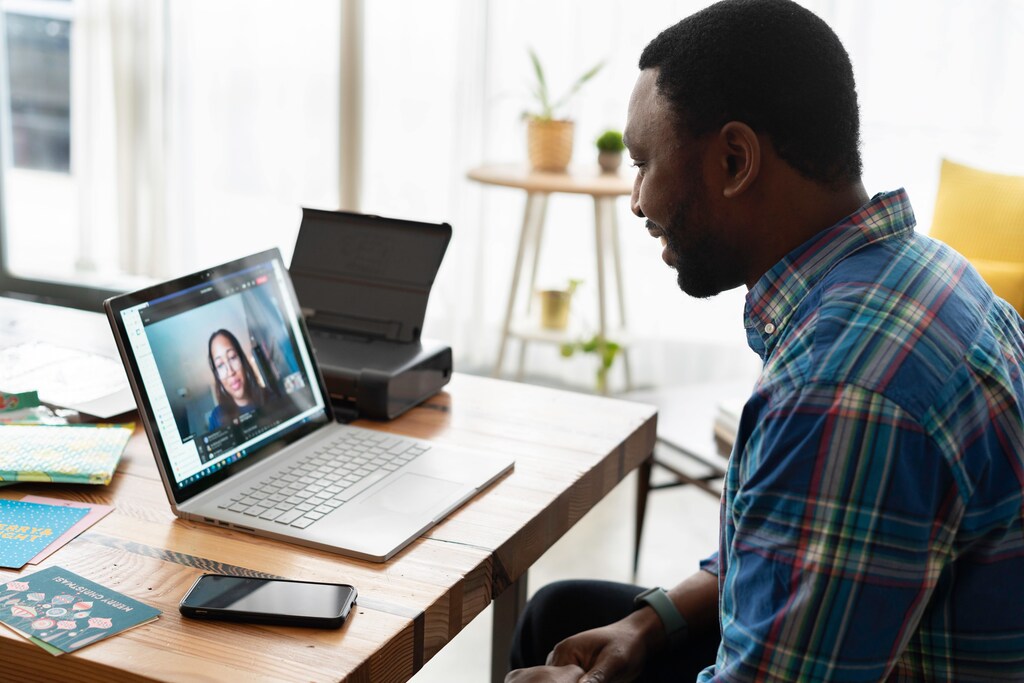 In-person communication: Man having a work meeting via zoom on his laptop.