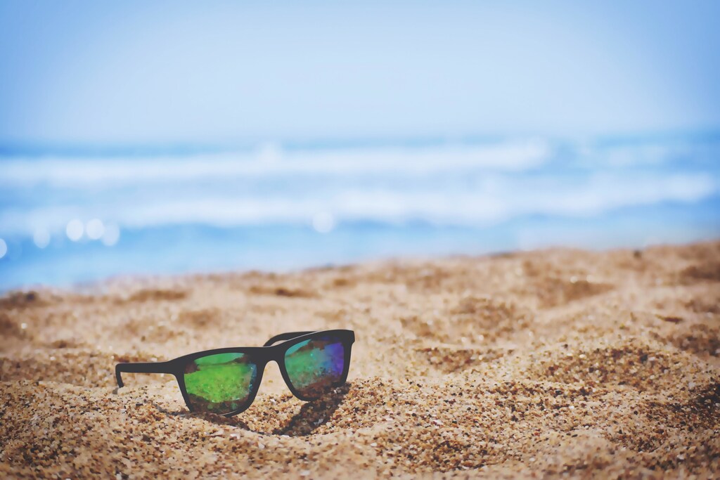 Close-up of sunglasses on sandy beach. Travel is set to increase across Europe this summer.