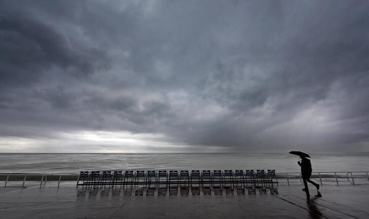 A man walks under an umbrella on the Promenade Des Anglais in Nice while heavy rain hits southern France November 25, 2014. REUTERS/Eric Gaillard (FRANCE - Tags: ENVIRONMENT)