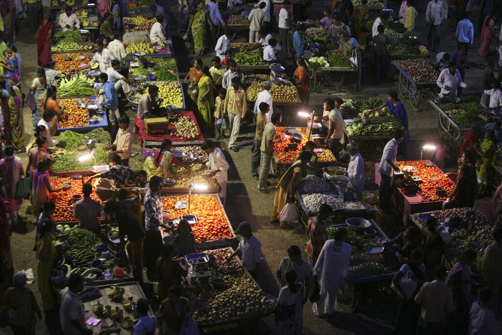 Vendors use solar powered lights at an open air evening market as customers buy fruits and vegetables in the western Indian city of Ahmedabad September 10, 2009. When night falls in remote parts of Africa and the Indian subcontinent, hundreds of millions of people without access to electricity turn to candles or flammable and polluting kerosene lamps for illumination. Slowly through small loans for solar powered devices, microfinance is bringing light to these rural regions where a lack of electricity has stymied economic development, literacy rates and health. Picture taken Sepetember 10, 2009. To match feature INDIA-SOLAR/ REUTERS/Amit Dave (INDIA ENERGY BUSINESS AGRICULTURE) - GM1E5AR0L7B01
