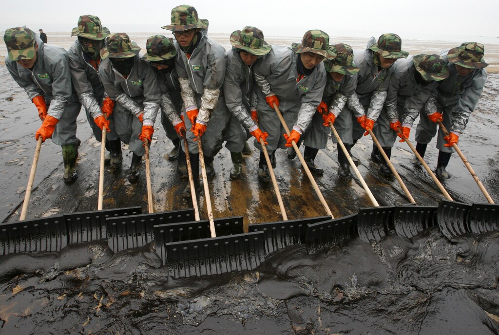 Soldiers from the South Korean army make efforts to remove crude oil spills over Mallipo swimming beach after after an accident involving Hong-Kong registered oil tanker Hebei Spirit in Taean, about 170km (106 miles) southwest of Seoul, December 10, 2007. South Korea on Monday was tallying the environmental and economic cost of the worst oil spill in its history as thousands of workers struggled to protect an area known for its nature reserve and vibrant marine economy. REUTERS/Jo Yong-Hak (SOUTH KOREA) - GM1DWTZOQAAA