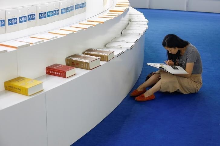 A woman reads a book at the Beijing International Book Fair in Beijing, China, August 23, 2017. REUTERS/Thomas Peter
