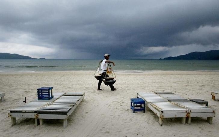 A Thai food vendor strolls past empty beach chairs as a storm approaches Patong Beach on the Southern Thai resort island of Phuket October 31, 2002.Thailand reassured tourists on Thursday that the country was safe despitewarnings from western nations such as Britain which said on Tuesday threatsto westerners on Phuket island had increased sharply. Phuket relies heavilyon the tourist trade and economists say a major fall in tourist arrivalswould slice a large chunk off Thailand's foreign exchange earnings and throwmillions of people out of work. NO RIGHTS CLEARANCES OR PERMISSIONS ARE REQUIRED FOR THIS IMAGE REUTERS/Jason ReedJIR/JS