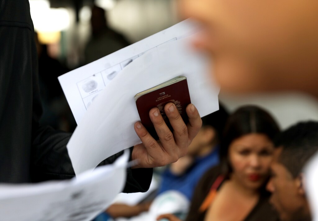 A Venezuelan migrant holds a passport as he queues to get the needed paperwork for a temporary residency permit at Interpol headquarters in Lima, Peru August 21, 2018. REUTERS/Mariana Bazo