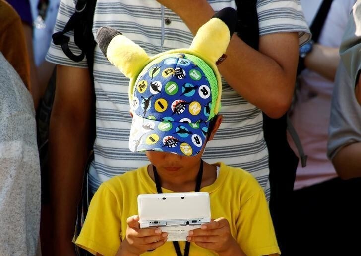 A boy plays Nintendo's game console prior to a parade where Pokemon's character Pikachu attends, in Yokohama, Japan, August 7, 2016. Picture taken on August 7, 2016. REUTERS/Kim Kyung-Hoon