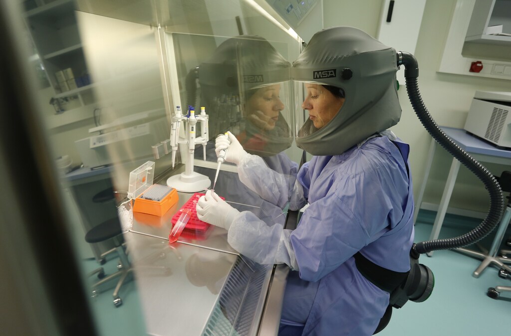 Dr. Doreen Muth from the virology institute of the Bonn Faculty of Medicine works under a flow head at a clean bench in a biosafety level three (BSL-3) laboratory in the western German city of Bonn May 31, 2013. The virology institute of the Bonn university researches on viruses with the help of bat and human cell culture models and reverse genetic systems for corona viruses (SARS-Coronavirus, HCoV-NL63) to characterize and compare the functions of homologous viral proteins from newly identified viruses. Picture taken May 31, 2013. REUTERS/Wolfgang Rattay (GERMANY - Tags: SCIENCE TECHNOLOGY HEALTH) - RTX11PFK