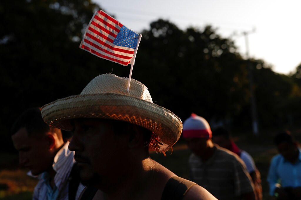 A migrant from Honduras, part of a caravan traveling to the U.S., wears a hat with the U.S. flag while he walks along the road to Huixtla, near Tapachula, Mexico, October 31, 2018. REUTERS/Carlos Garcia Rawlins - RC14FAA773D0