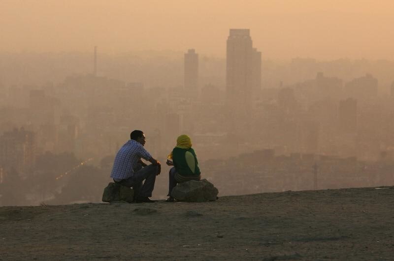 An Egyptian couple chat at the top of a mountain area that looks over Cairo during a smoggy day July 12, 2008 REUTERS/Asmaa Waguih (EGYPT) - GM1E47D07VG01