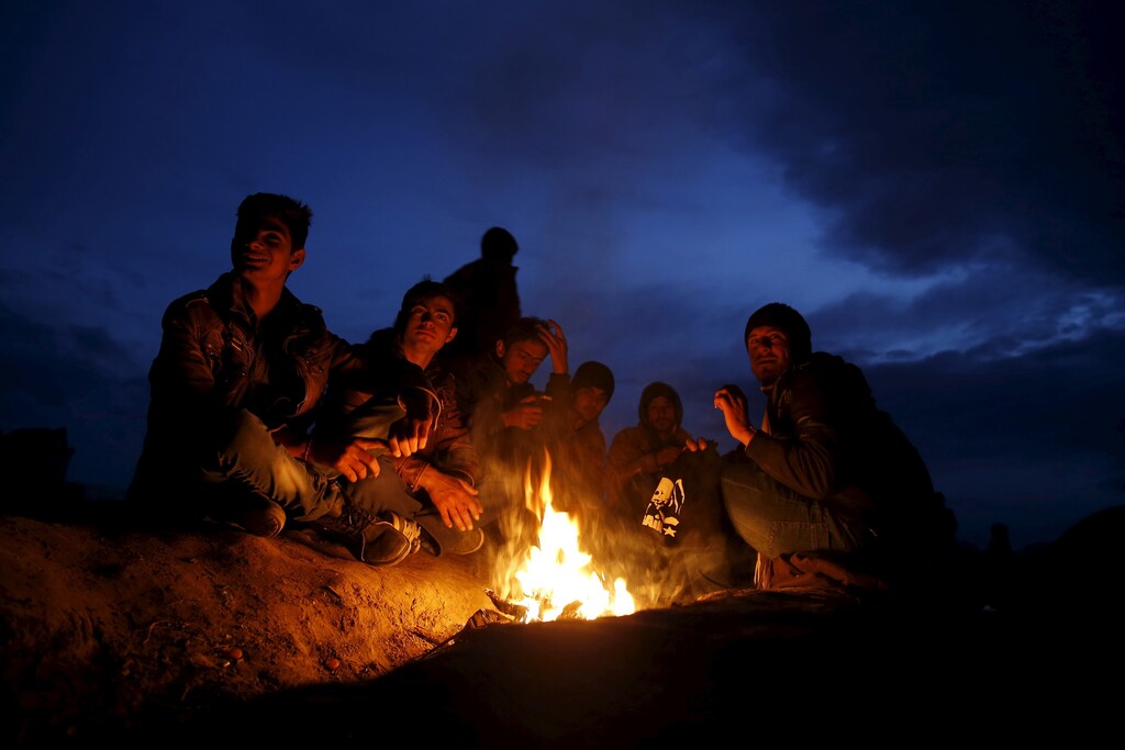 Migrants who are waiting to cross the Greek-Macedonian border, sit by the fire near the village of Idomeni, Greece, March 3, 2016. REUTERS/Marko Djurica - GF10000332225