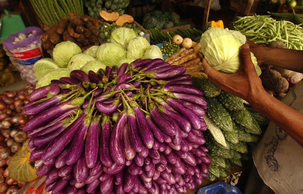 A vendor holds a cabbage at his stall after heavy rains in the morning at a main market in Colombo June 28, 2013. Lack of supply of fish and seafood due to bad weather contributed to the rise in inflation, government data showed. Core annual inflation, which excludes fresh food, energy, transport, rice and coconuts, eased to a record low of 4.3 percent in June from 5.7 percent a month ago, according to the new consumer price index introduced in mid-2011. REUTERS/Dinuka Liyanawatte (SRI LANKA - Tags: BUSINESS) - GM1E96S1KYM01