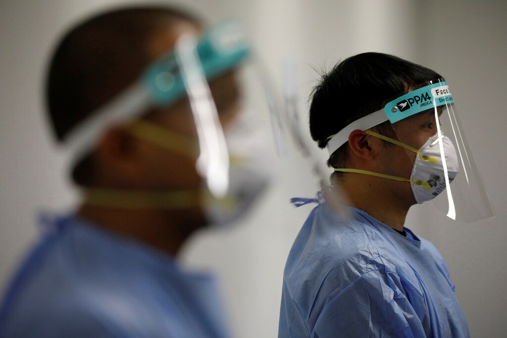 Security personnel who are dressed in PPE (Personal Protective Equipment) stand at a check-in area at Changi Exhibition Centre which has been repurposed into a community isolation facility that will house recovering or early COVID-19 patients with mild symptoms, during the coronavirus disease (COVID-19) outbreak, in Singapore April 24, 2020. Picture taken April 24, 2020. REUTERS/Edgar Su - RC24CG9G9I84