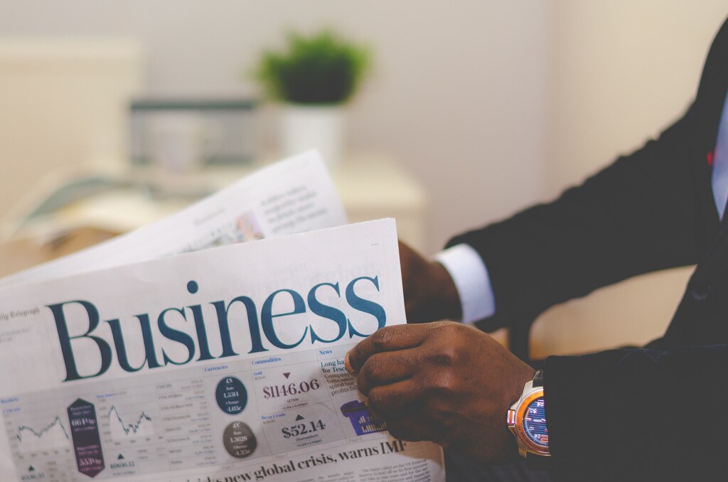 Person wearing suit opening a newspaper.