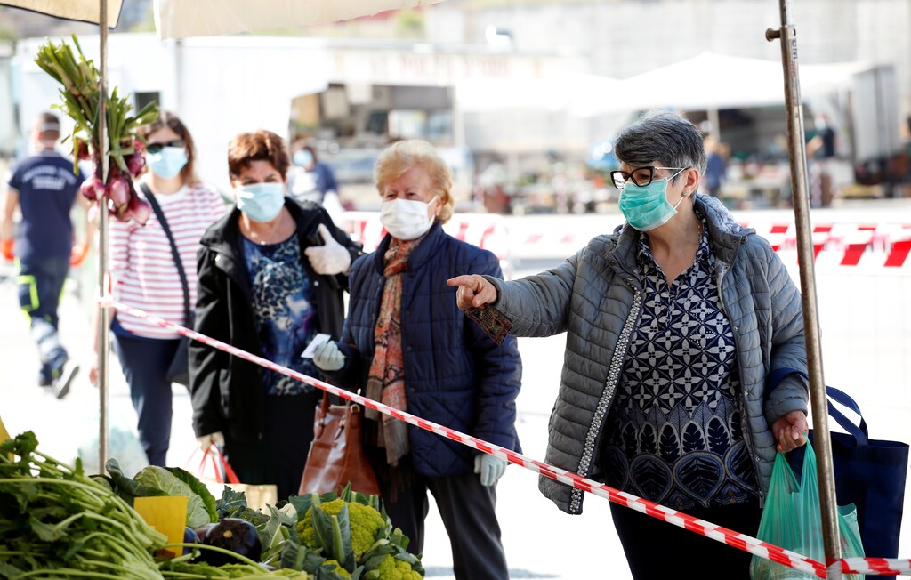 People wearing protective face masks queue in line at an open-air food market that has been reopened, during the coronavirus disease (COVID-19) outbreak in Cisternino, Italy, April 27, 2020. REUTERS/Alessandro Garofalo - RC2ZCG9DYETM