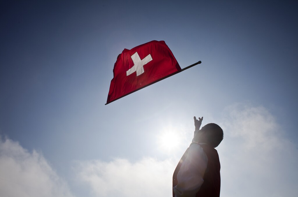 A man throws a Swiss national flag in the air