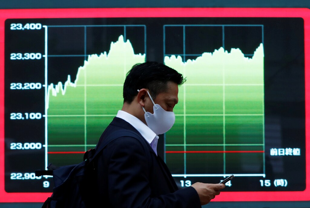 A man wearing a protective face mask walks past a screen displaying a graph showing recent Nikkei share average outside a brokerage, amid the coronavirus disease (COVID-19) outbreak, in Tokyo, Japan November 2, 2020. REUTERS/Issei Kato - RC2WUJ9AK39T