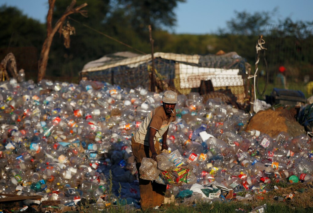 A man collects waste materials including plastic bottles to be recycled at an informal settlement in Kliptown, Soweto, South Africa, February 27, 2019. REUTERS/Siphiwe Sibeko - RC11D7E07E50