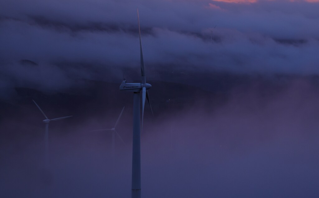 Wind turbines in dark fog. Wind energy is becoming a strategic tool for states aiming to bolster their energy independence and improve resilience to supply chain shocks.