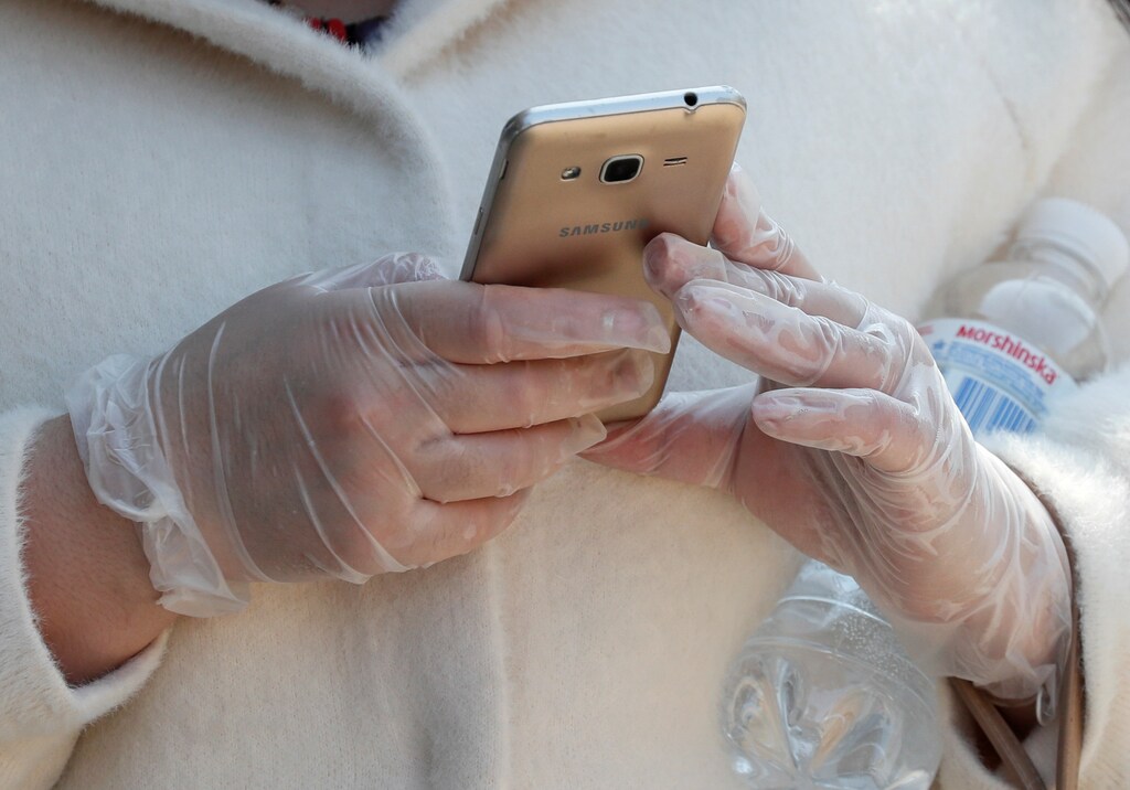 A woman wearing protective gloves, as a preventive measure against the coronavirus disease (COVID-19), uses her mobile phone in central Kiev, Ukraine April 7, 2020. REUTERS/Gleb Garanich - RC2QZF9D91T3