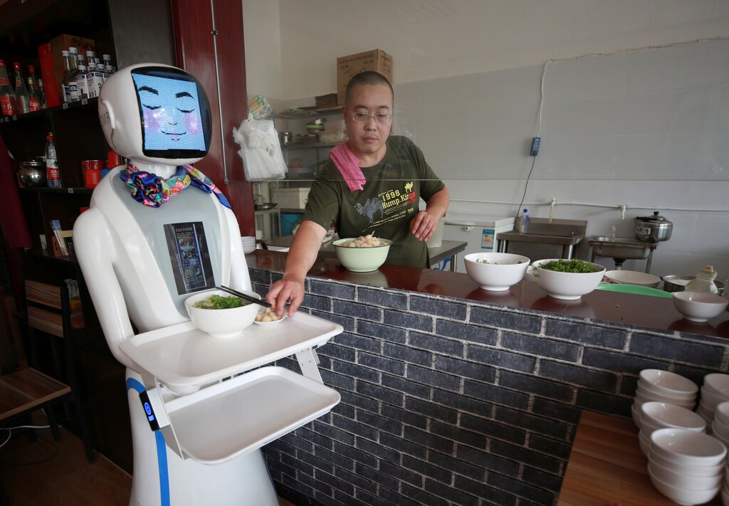 A chef places plates with food onto the tray of a robot waiter in a restaurant in Xianyang, China June 17, 2017. Picture taken June 17, 2017. REUTERS/Stringer TPX IMAGES OF THE DAY ATTENTION EDITORS - THIS IMAGE WAS PROVIDED BY A THIRD PARTY. CHINA OUT. NO COMMERCIAL OR EDITORIAL SALES IN CHINA. - RC1E08E544F0