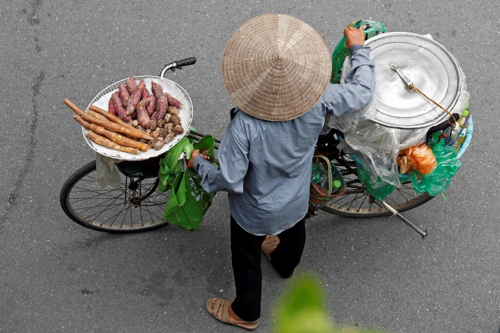 A Vietnamese woman transports cooked cassava and potato for sale by a bicycle on a street in Hanoi, Vietnam August 29, 2017. REUTERS/Kham - RC1ED76929E0