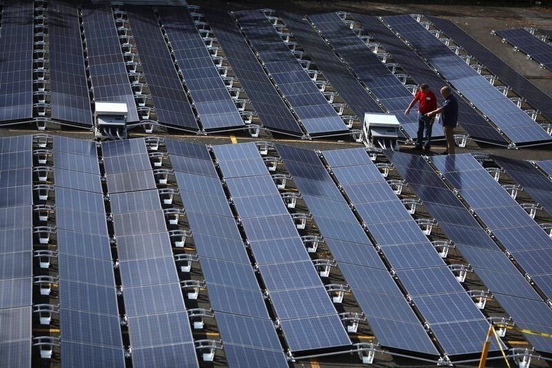 Men gesture next to solar panels set up by Tesla, at the San Juan Children's Hospital, after the island was hit by Hurricane Maria in September, in San Juan, Puerto Rico October 26, 2017. REUTERS/Alvin Baez - RC170359F4E0
