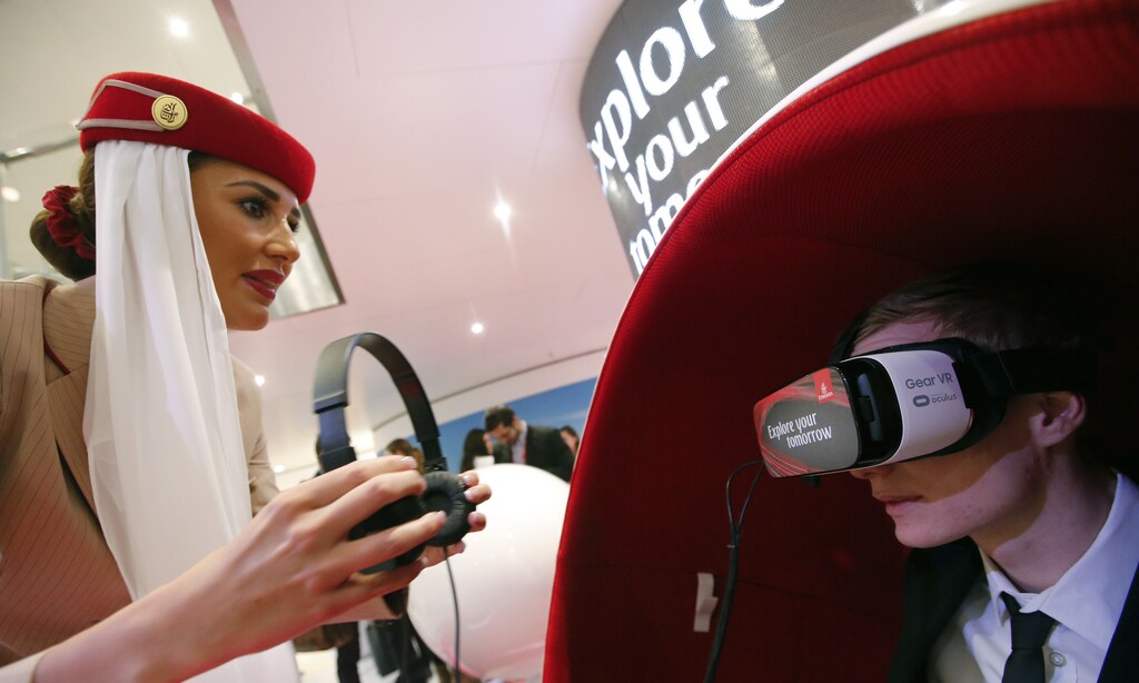 An Emirates Airlines flight attendant assists a visitor using a Gear VR virtual reality headset by Oculus and Samsung Electronics, at the Emirates Airlines exhibition stand during the International Tourism Trade Fair (ITB) in Berlin, Germany, March 9, 2016. REUTERS/Fabrizio Bensch - RTSA0DU