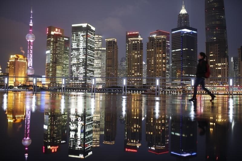 A woman walks at the Bund in front of the financial district of Pudong in Shanghai March 5, 2015. China aims to grow its economy by around 7 percent in 2015 and to keep consumer inflation at around 3 percent, Premier Li Keqiang said in remarks prepared for delivery at today's opening of the annual meeting of parliament, the National People's Congress. REUTERS/Aly Song (CHINA - Tags: POLITICS BUSINESS TPX IMAGES OF THE DAY) - RTR4S5ZO