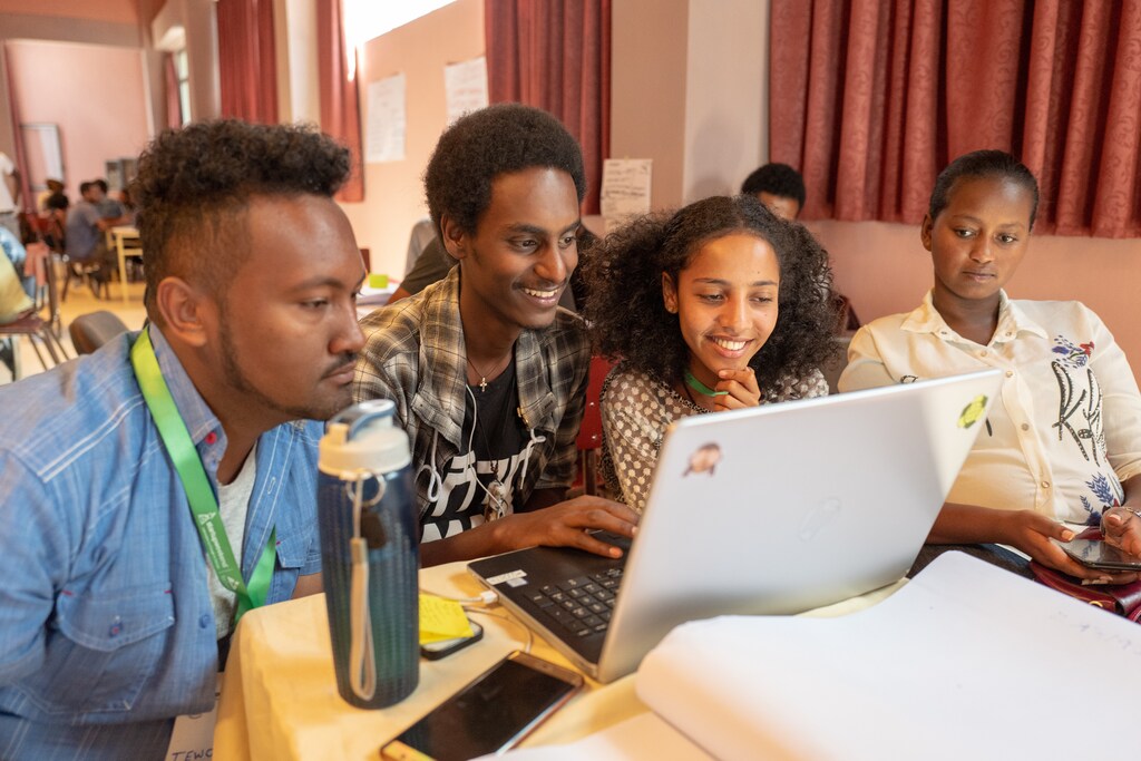 four young people work on a laptop