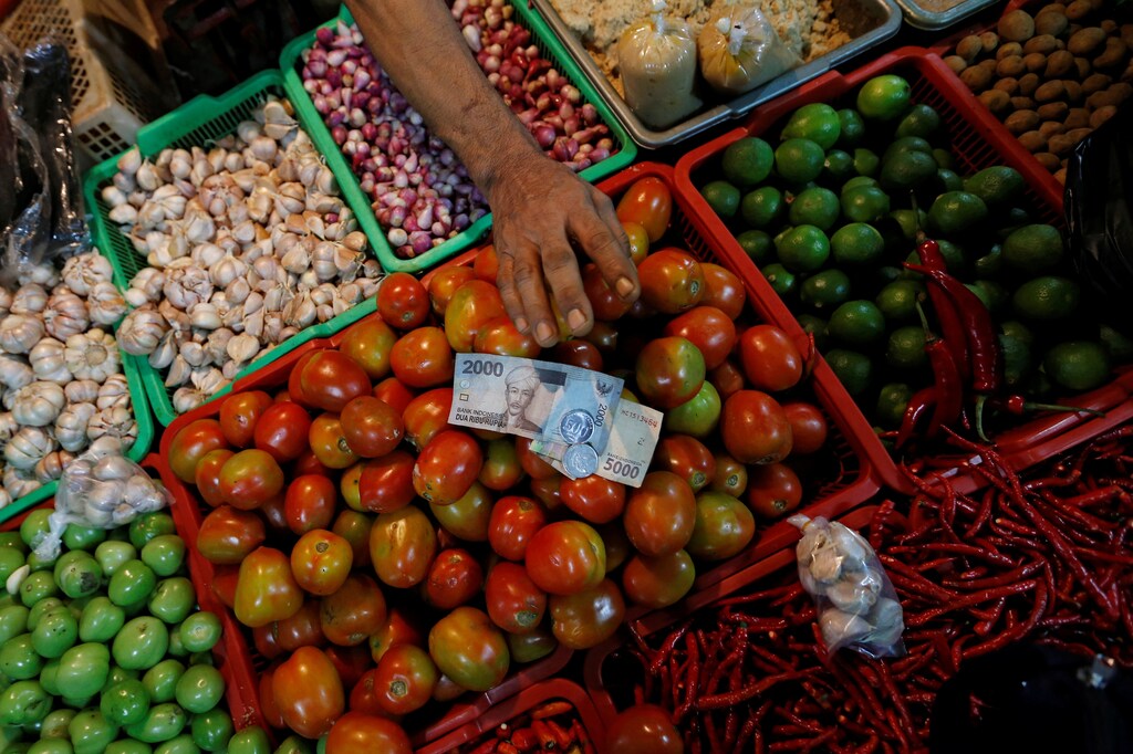 A vegetable vendor takes money from the customer during a transaction at a traditional market in Jakarta, Indonesia, May 2, 2019. REUTERS/Willy Kurniawan - RC1888891E90