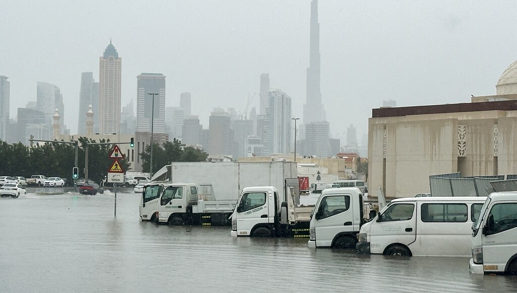Vehicles stand in flood water caused by heavy rains with the Burj Khalifa tower visible in the background, in Dubai.