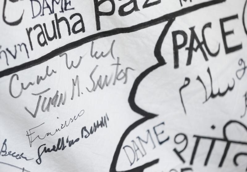 The autographs of German Chancellor Angela Merkel and Colombian President Juan Manuel Santos are seen near a Pope Francis sign on a Peace flag after their visit in Assisi, Italy, May 12, 2018.
