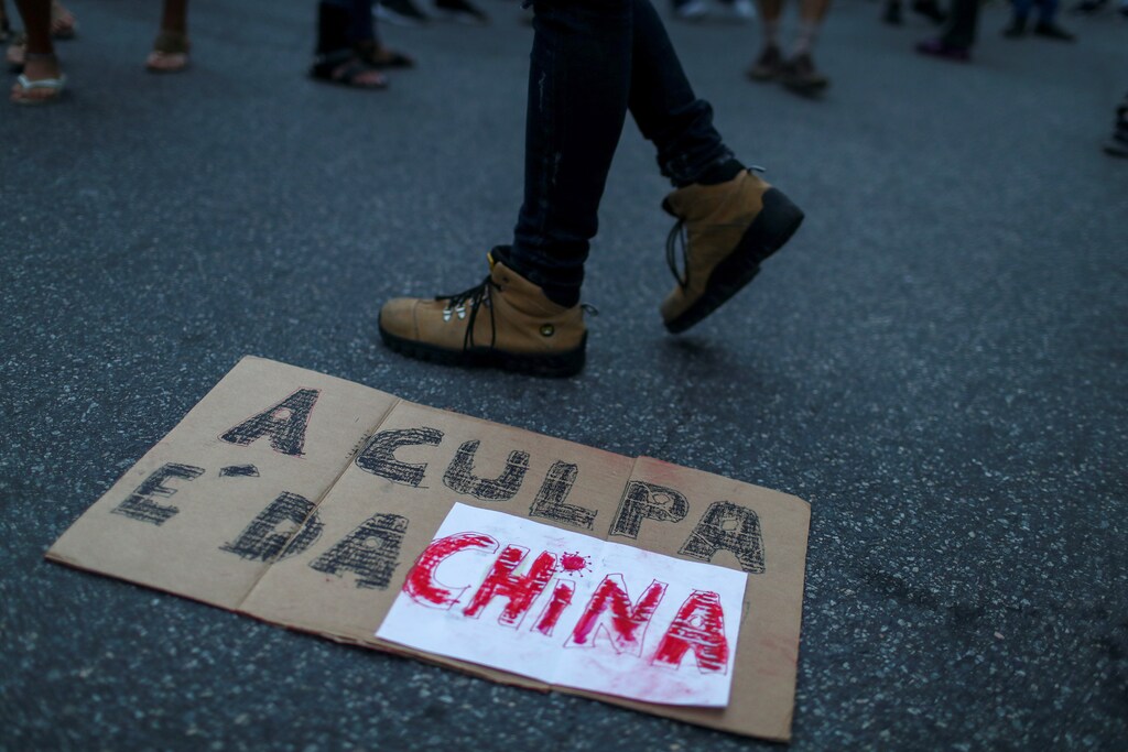 A person walks past a sign laying on the ground that reads: "It's China's fault" as supporters of Brazil's President Jair Bolsonaro take part in a protest blaming China for being the country where the coronavirus disease (COVID-19) started, in front of the Chinese consulate in Rio de Janeiro, Brazil May 17, 2020.