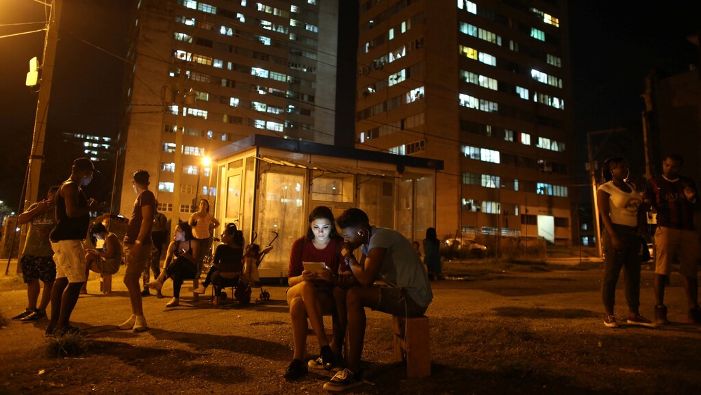Carolina Gutierrez (center L), 17, and Neuil Valdez, 18, use mobile phones to connect to the internet at a hotspot in downtown Havana, Cuba, December 12, 2016.