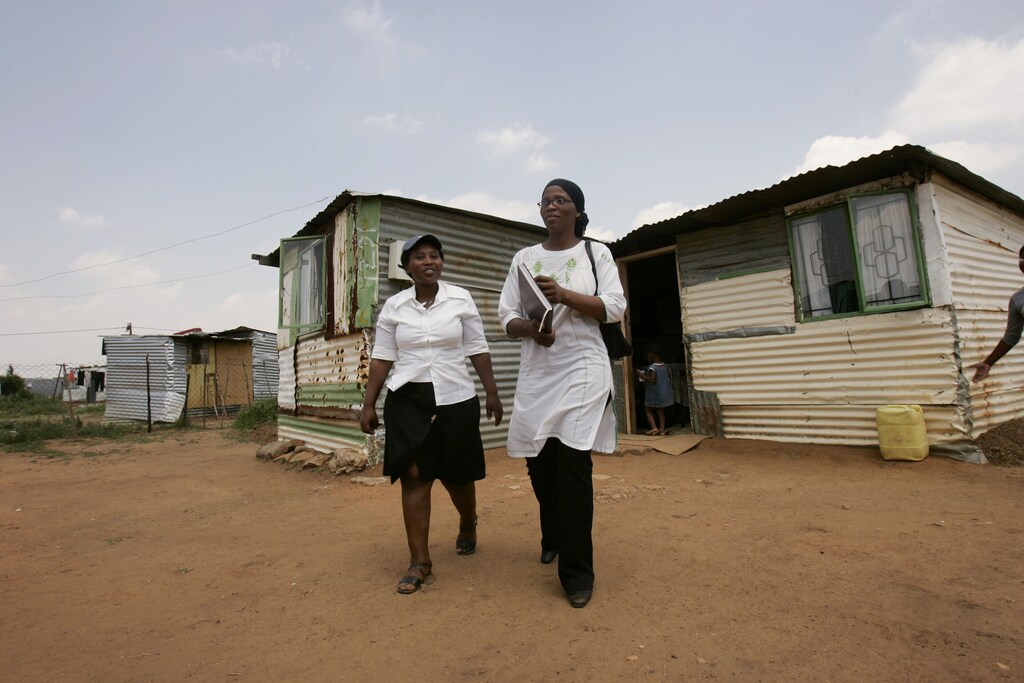 HIV/AIDS patient and AIDS organization owner Valencia Mofokeng (R), and Bongiwe Mqikela leave a patient's house in Orange Farm outside Johannesburg November 29, 2006. South Africa will unveil a new plan aimed at fighting its HIV/AIDS crisis on Friday, seeking to calm bitter debate and revise policies that have thus far done little to stop the epidemic. REUTERS/Siphiwe Sibeko (SOUTH AFRICA)