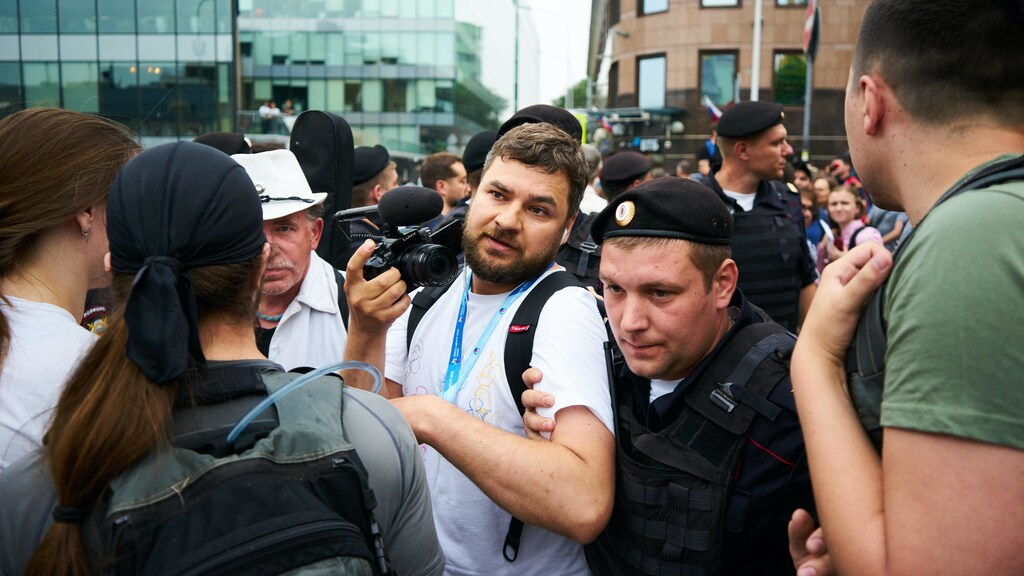 A journalist being escorted away by a security officer