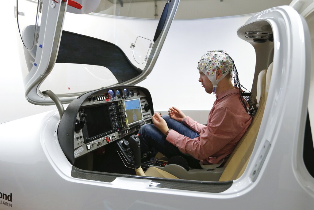 Test person Niklas Thiel sits inside a flight simulator with an electroencephalography (EEG) cap measuring brain activity, at the Technische Universitaet Muenchen (TUM) in Garching near Munich September 9, 2014. The researchers from TUM and the Technische Universitaet Berlin (team Phypa) try to find ways to control an airplane with computer translated brain impulses without the pilot touching the plane's controls. The solution, if achieved, would contribute to greater flight safety and reduce pilots' workload. Picture taken September 9, 2014. REUTERS/Michaela Rehle (GERMANY - Tags: SOCIETY SCIENCE TECHNOLOGY) - RTR45SH0