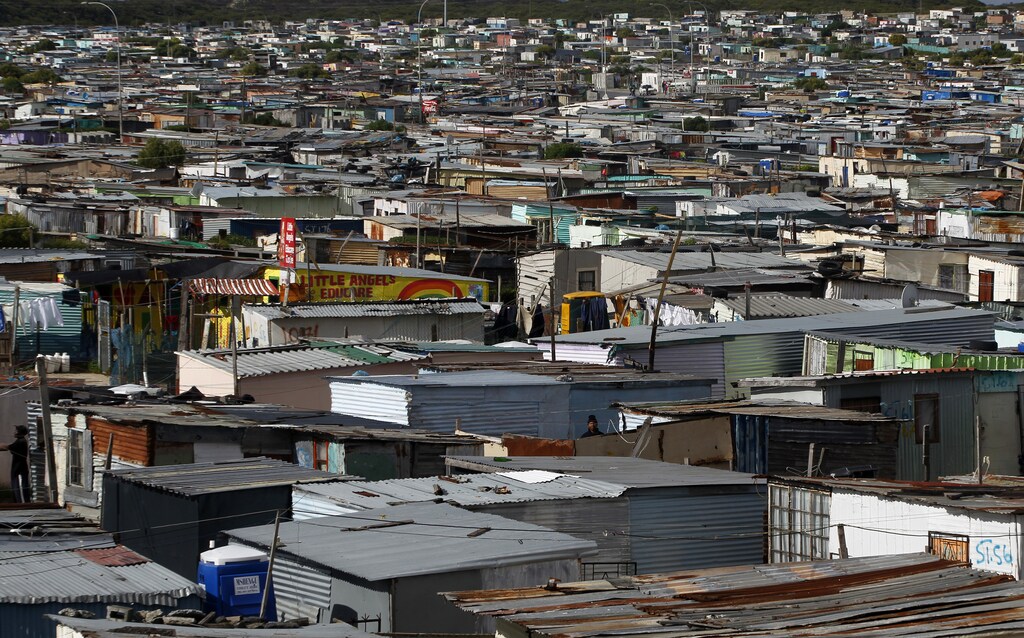 Residents walk through shacks in Cape Town's crime-ridden Khayelitsha township in this picture taken July 9, 2012. At least 11 people have died at the hands of vigilantes in the township since January as angry residents, tired of poor policing, take the law into their own hands. Picture taken July 9, 2012. To match Feature SAFRICA-CRIME/ REUTERS/Mike Hutchings (SOUTH AFRICA - Tags: CRIME LAW) - GM1E87C1UFL01