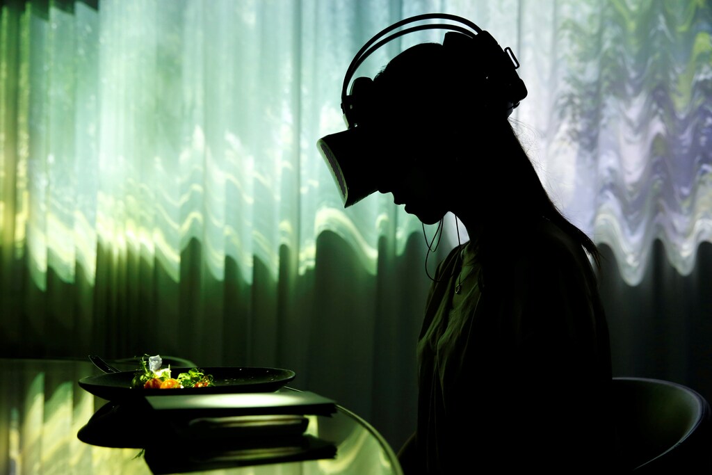 A woman wears VR glasses while the projection mapping is cast on table and walls during its media preview at "TREE BY NAKED, yoyogi park" restaurant in Tokyo, Japan, July 19, 2018. This restaurant incorporates virtual reality, projection mapping, and music to enhance diners' enjoyment of their food. REUTERS/Kim Kyung-Hoon TPX IMAGES OF THE DAY - RC1D7B15FD20