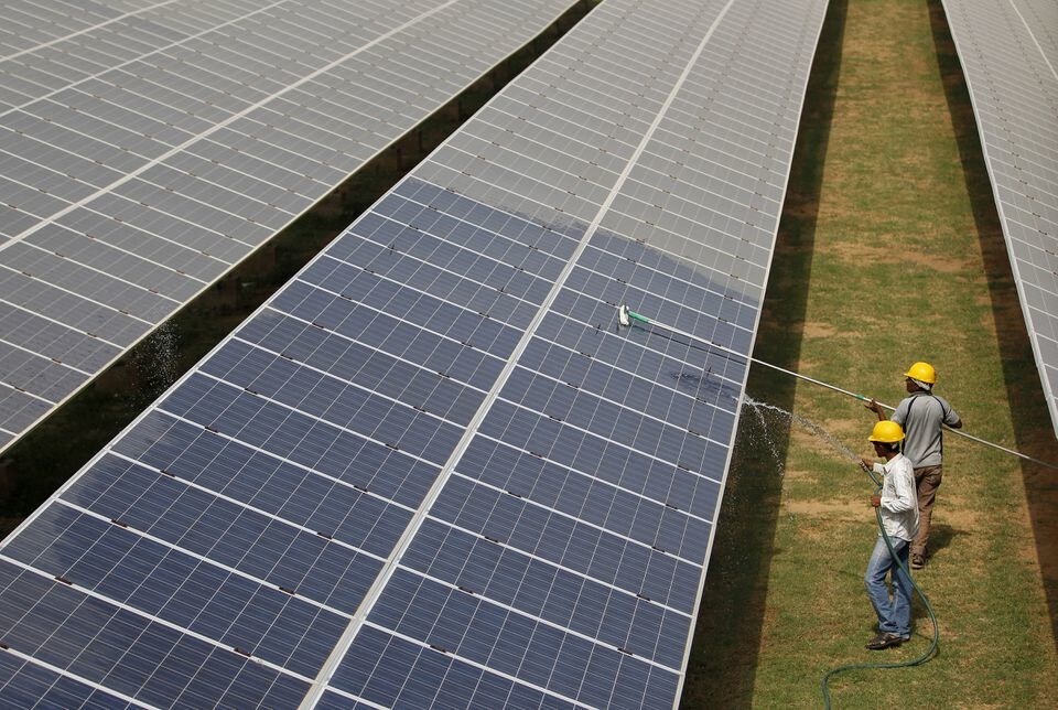 Workers clean solar photovoltaic panels in Gujarat, India.