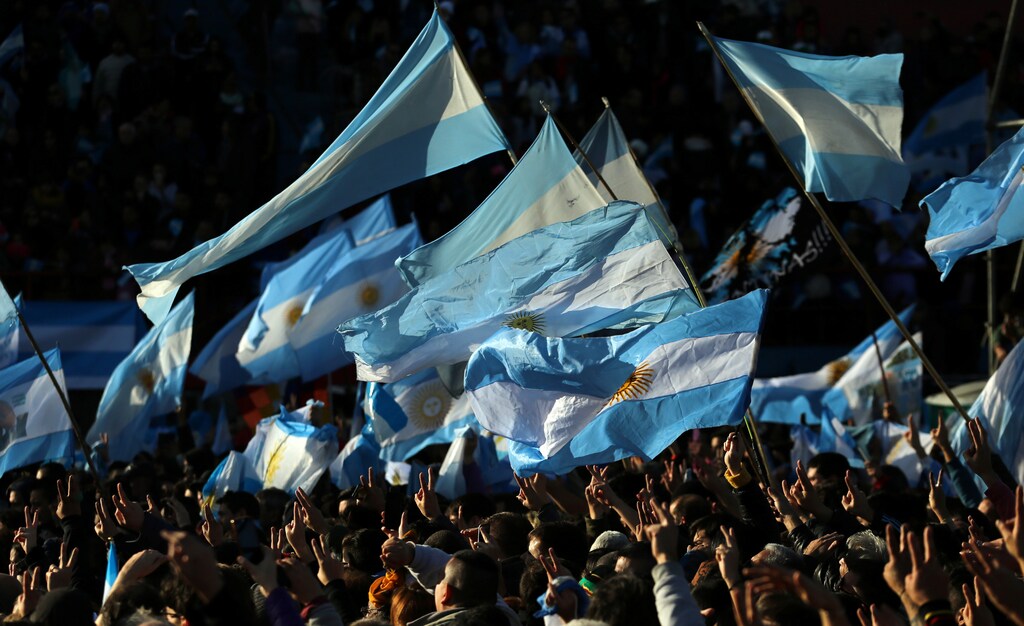 Supporters of former Argentine President Cristina Fernandez de Kirchner flash the victory sign and wave Argentine national flags as they attend a rally to commemorate flag day in Buenos Aires, Argentina June 20, 2017. REUTERS/Marcos Brindicci - RTS17XPG