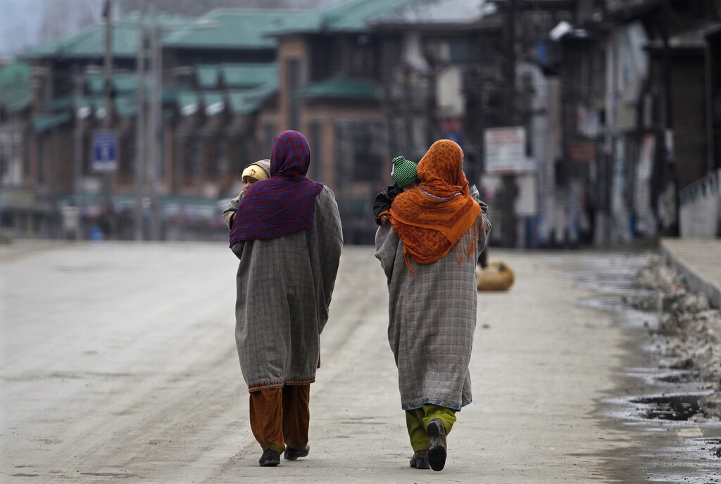 Kashmiri Muslim women carry their babies while walking through a deserted road as authorities imposed restrictions in Srinagar February 9, 2014. Authorities imposed restrictions across Srinagar as separatists called for a three-day shutdown to demand the remains of Mohammad Afzal Guru, a Kashmiri man who was executed on February 9, 2013, for an attack on India's parliament in 2001, local media reported on Sunday. REUTERS/Danish Ismail (INDIAN-ADMINISTERED KASHMIR - Tags: CIVIL UNREST POLITICS SOCIETY) - GM1EA291D1601