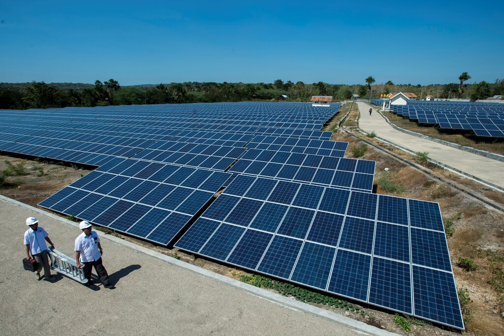 State Electricity Company officials walk near solar cell panels at the largest solar power plant in Indonesia, at Oelpuah village in Kupang, July 20, 2017 in this photo taken by Antara Foto. Picture taken July 20, 2017. Antara Foto/Widodo S Jusuf via REUTERS ATTENTION EDITORS - THIS IMAGE WAS PROVIDED BY A THIRD PARTY. FOR EDITORIAL USE ONLY. MANDATORY CREDIT. INDONESIA OUT. NO COMMERCIAL OR EDITORIAL SALES IN INDONESIA. - RC110FF7D460