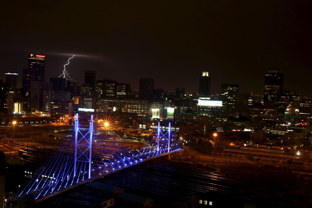 Lighting flashes in the sky over the Nelson Mandela Bridge, a Johannesburg landmark, as it is lit up in blue to mark the 70th anniversary of the United Nations, in South Africa October 24, 2015. REUTERS/Siphiwe Sibeko - GF20000031498