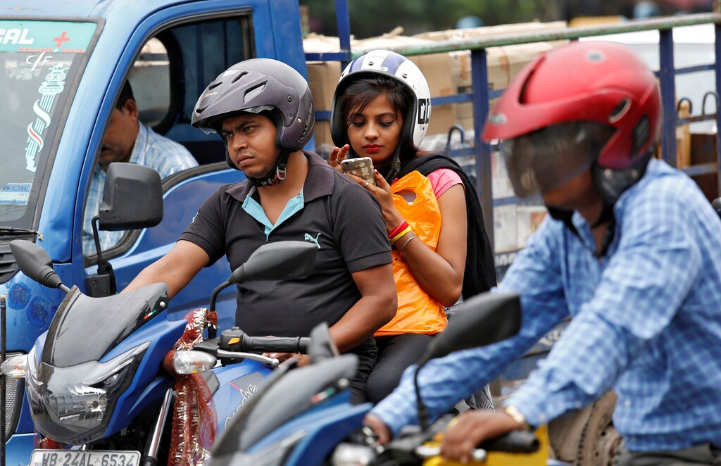 A woman checks her mobile phone at a traffic junction in Kolkata, India July 5, 2017. REUTERS/Rupak De Chowdhuri - RC17240A8A40